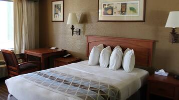 A hotel room with a large bed, a desk, a chair, and two wall-mounted lamps.