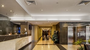 Un hall de hotel con mostrador de recepción, un árbol de Navidad y un moderno ascensor.