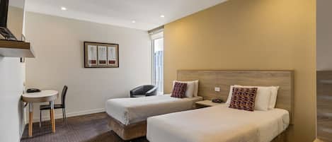 A hotel room with two beds, a desk, and a chair.