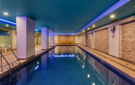 A swimming pool with a tiled floor, surrounded by walls with a stone-like texture.