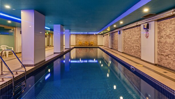 Una piscina con suelo de baldosas, rodeada de paredes con textura similar a la piedra.