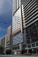 Un moderno edificio de gran altura con varios pisos, ventanas amplias y un área de entrada destacada.