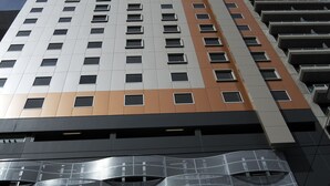 Un edificio de gran altura con un diseño arquitectónico moderno, que presenta una serie de balcones y fachada reflectante.