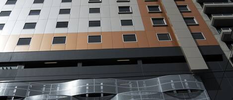 Un edificio de gran altura con un diseño arquitectónico moderno, que presenta una serie de balcones y fachada reflectante.