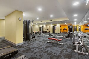 Un gimnasio con equipo cardiovascular, máquinas de pesas y un espejo grande.