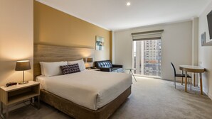 Una habitación de hotel con una cama grande, un escritorio, una silla y una mesita.