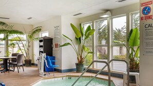 Un espace piscine intérieur avec des règles claires affichées, un panneau indiquant qu’il est interdit de plonger et un système de chauffage pour la piscine.
