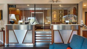Un espace d’accueil avec une cloison en verre, un comptoir d’accueil, un escalier et un canapé bleu.