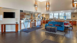 Un hall d’hôtel moderne avec un comptoir d’accueil, un canapé bleu et un coin cuisine.