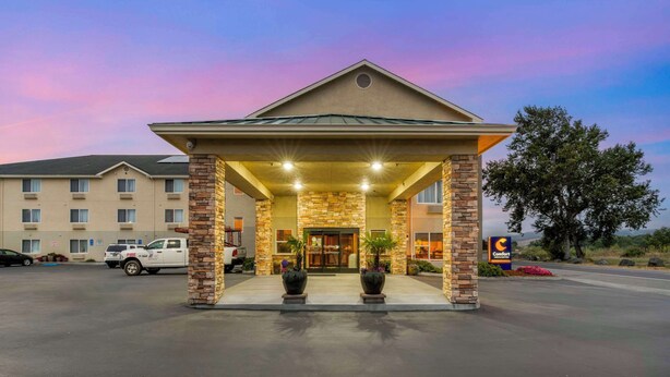 L’entrée d’un hôtel, avec une façade en briques, un espace abrité et une enseigne indiquant « Comfort Suites ».