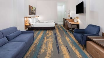 Een hotelkamer met een bed, een bureau, een stoel, een bank en een televisie.