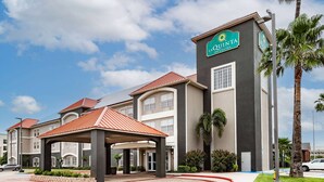 Un hôtel au design moderne, avec une grande enseigne indiquant « La Quinta Inn & Suites ».