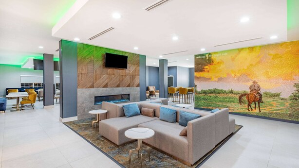 Un hall d’entrée moderne avec un canapé d’angle, une cheminée et une fresque représentant un cheval.