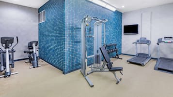 A gym with exercise equipment, a TV, and a patterned wall.