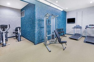 Un gimnasio con equipo de ejercicio, un televisor y una pared con diseño.