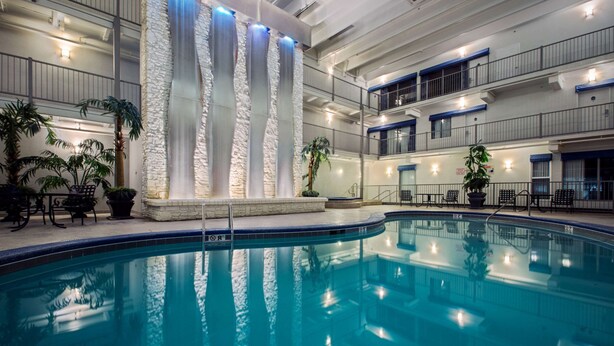 An indoor swimming pool with a stone wall and blue lighting. - Quality Inn Branson - Hwy 76 Central (Branson)