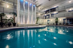 An indoor swimming pool with a stone wall and blue lighting. - Quality Inn Branson - Hwy 76 Central (Branson)