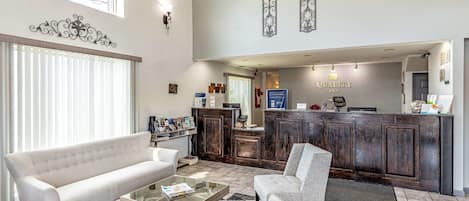 A hotel lobby with a reception desk, a sofa, a chair, and a coffee table.