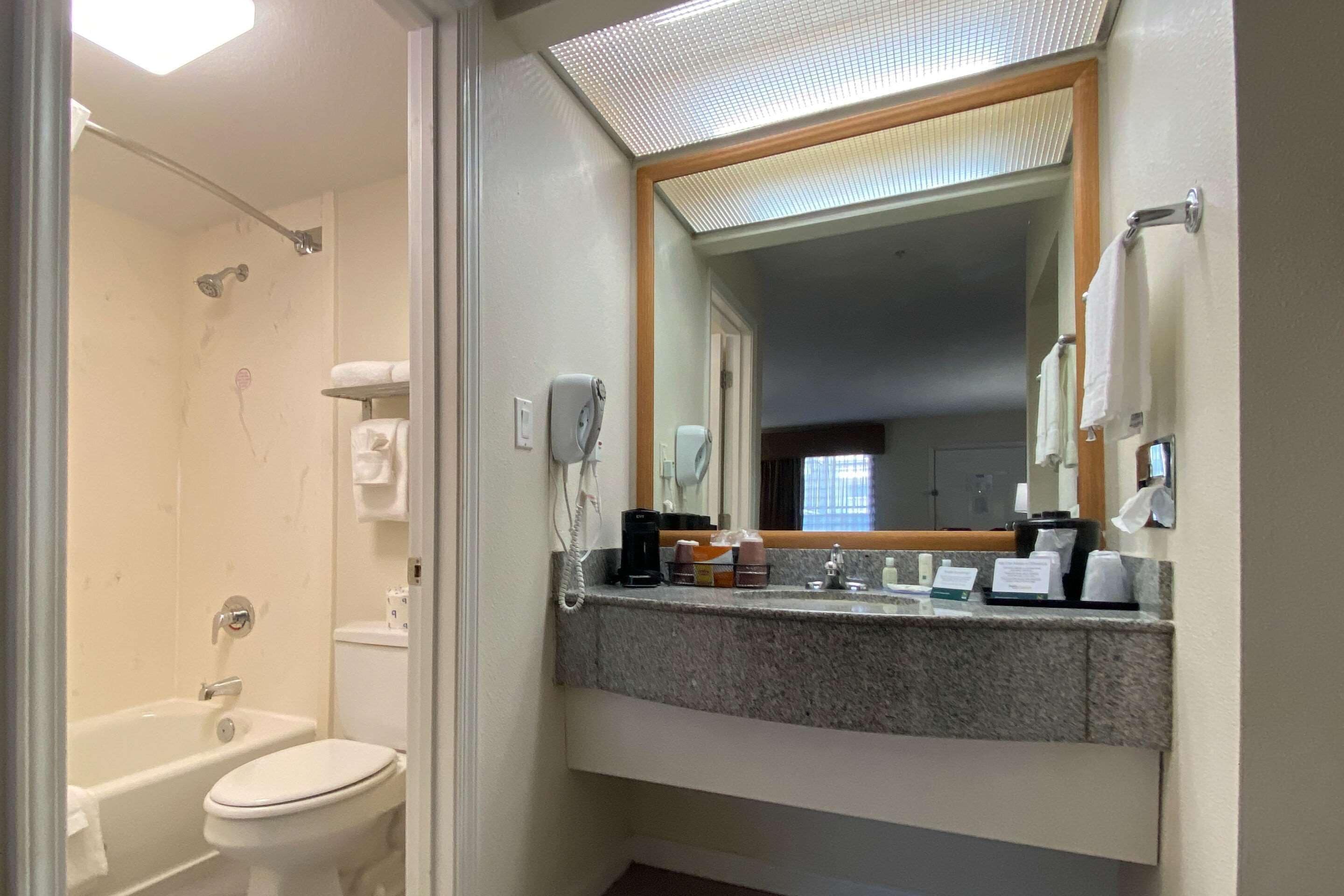 Un baño con bañera, inodoro y tocador con espejo.