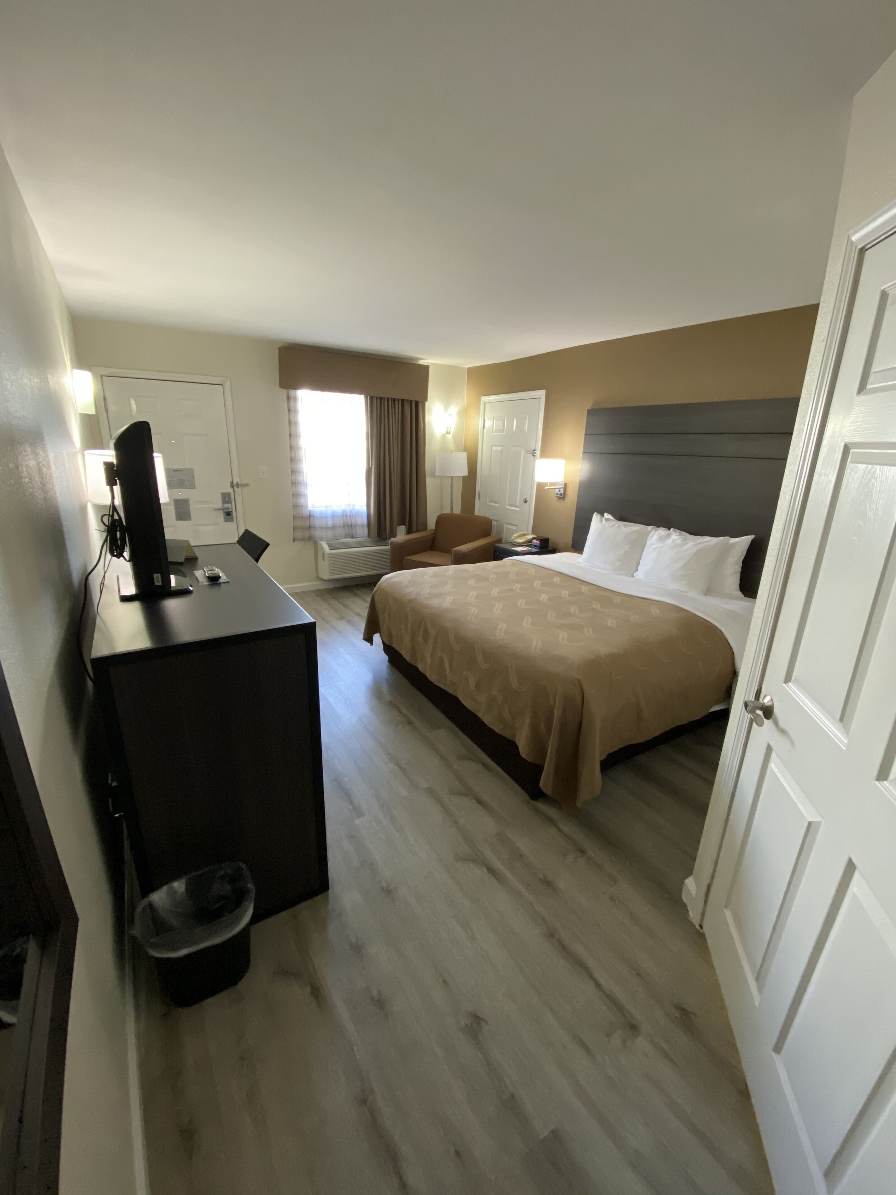 A hotel room with a bed, desk, chair, and a television.
