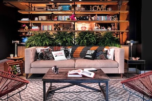 Relax in this inviting living room with a sofa, bookshelf, and potted plant.