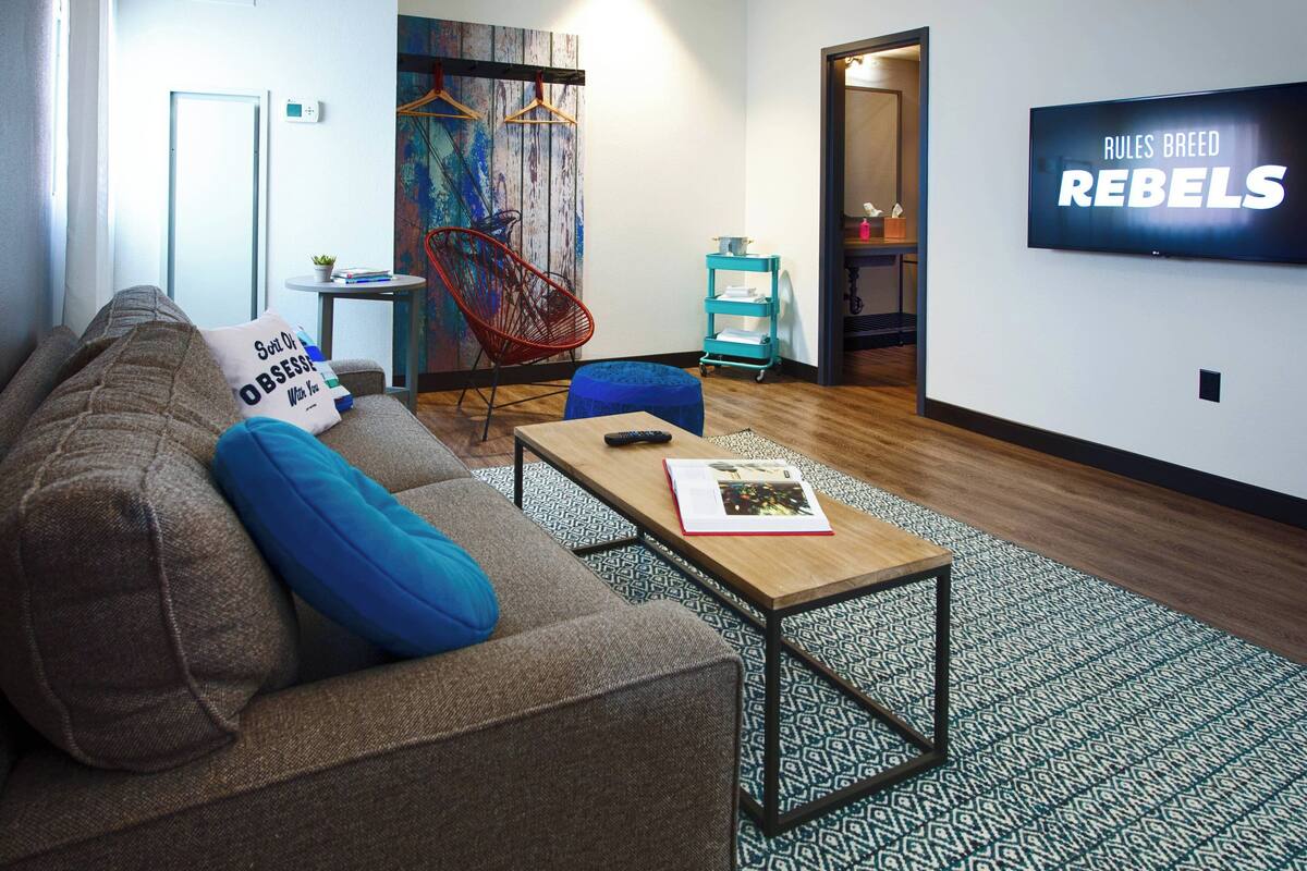 A modern living room with a sofa, coffee table, and a TV mounted on the wall.
