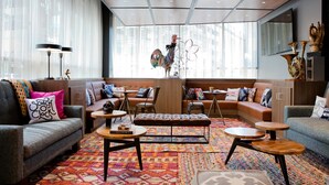 A modern living room with a sofa, ottoman, coffee table, and a patterned rug.