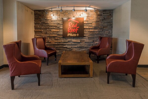 A lounge area with leather chairs, a wooden coffee table, and a stone wall with a sign.