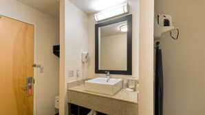 A bathroom with a sink, mirror, towel rack, and a door.