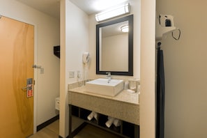 Un bagno con lavandino, specchio, porta asciugamani e porta.