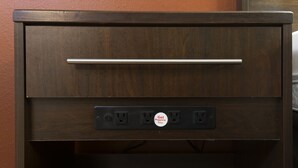 A wooden drawer with a metal handle and a power strip with a plug.