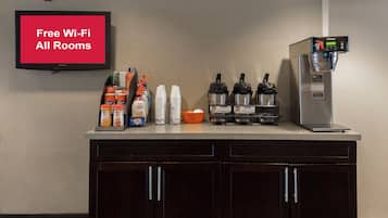 A kitchenette with a coffee machine, coffee pods, and a TV displaying 'Free Wi-Fi All Rooms'.