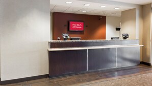 Un mostrador de recepción con una pantalla digital que muestra 'Wi-Fi gratuito en todas las habitaciones' y un terminal de pago.