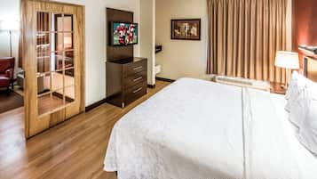 A hotel room with a bed, a television, a wardrobe, a desk, and a window with curtains.