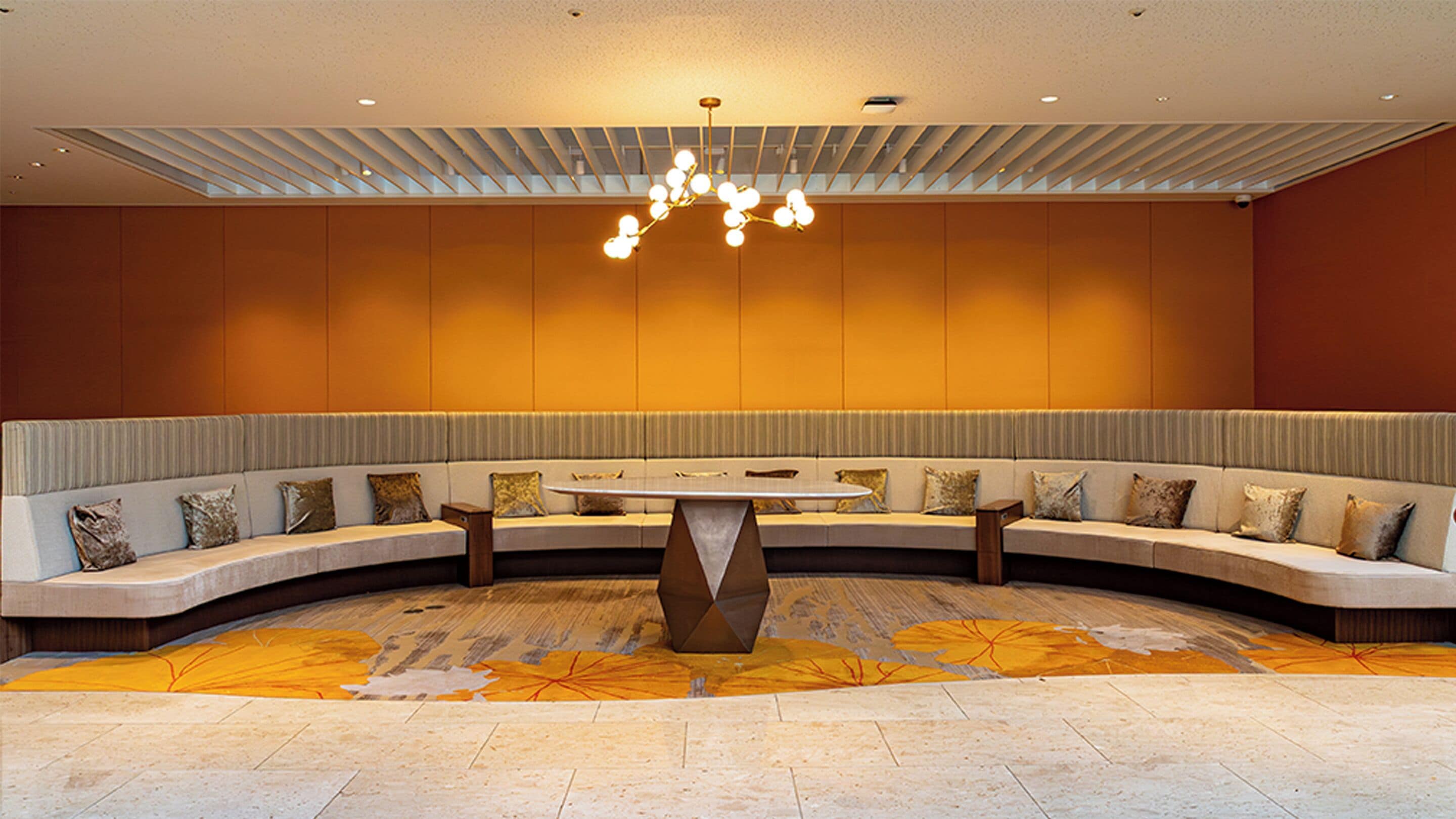 A modern lounge area with a curved seating arrangement, a central table, and a patterned carpet.