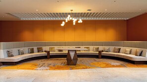 A modern lounge area with a curved seating arrangement, a central table, and a patterned carpet. - Phoenix Seagaia Ocean Tower (Miyazaki)