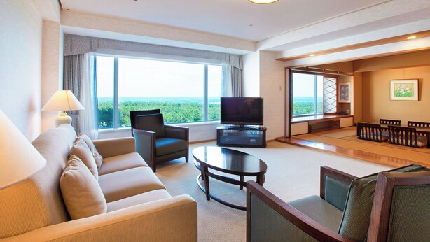 A hotel room with a sofa, armchair, TV, and tatami mats. - Phoenix Seagaia Ocean Tower (Miyazaki)