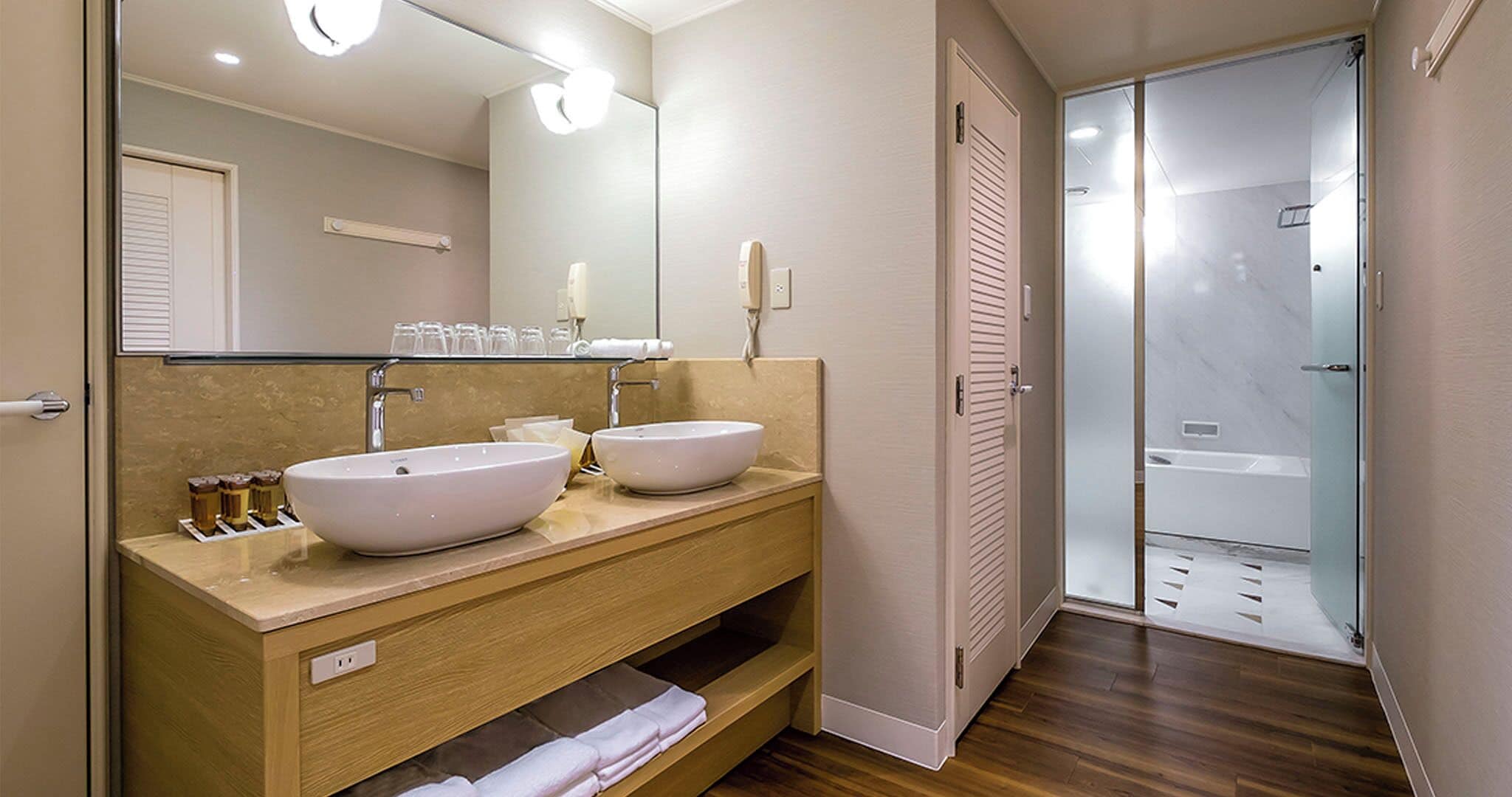 Une salle de bain moderne avec deux lavabos, un miroir et une douche à parois de verre.