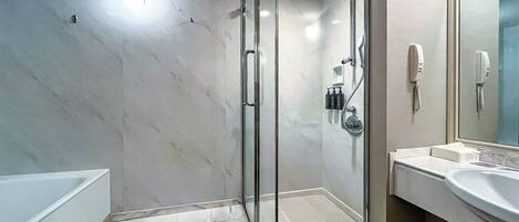 Un baño moderno con ducha envuelta en vidrio, una bañera blanca y un espejo grande sobre el lavamanos.