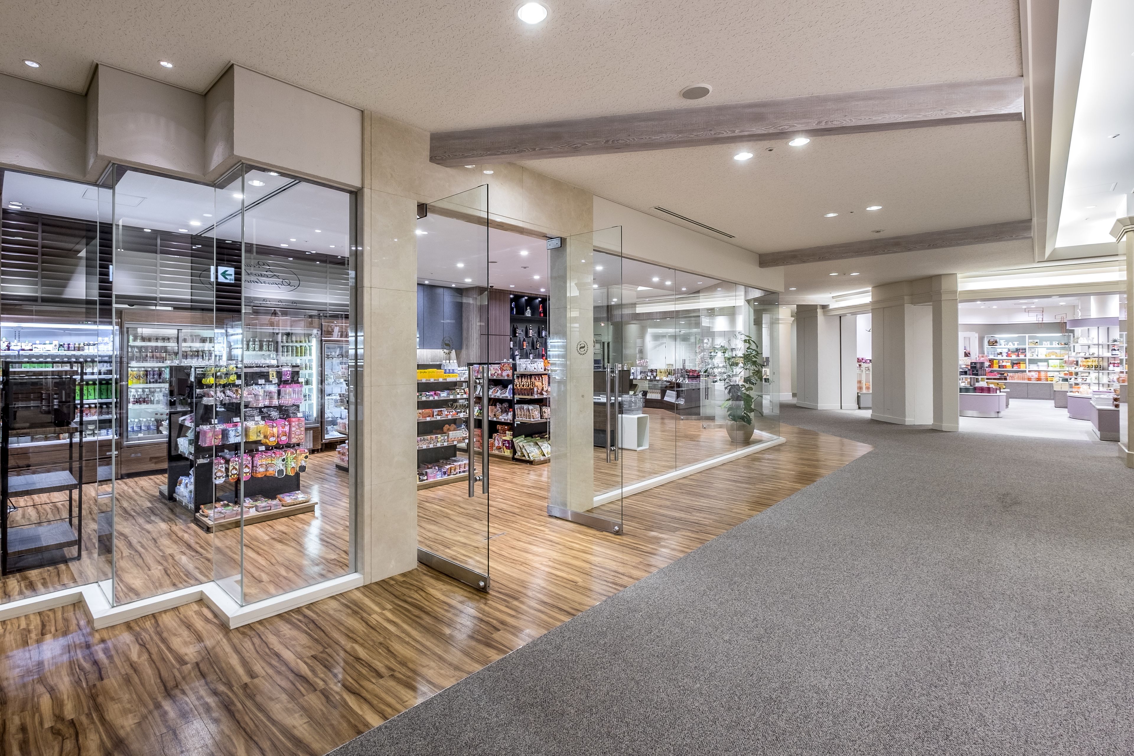 A spacious, modern retail store with glass display cases and wooden flooring.