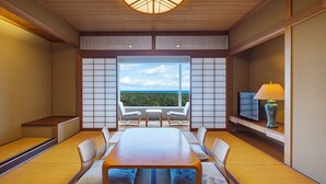A room with a wooden table, chairs, a TV, and a view of the ocean. - Phoenix Seagaia Ocean Tower (Miyazaki)