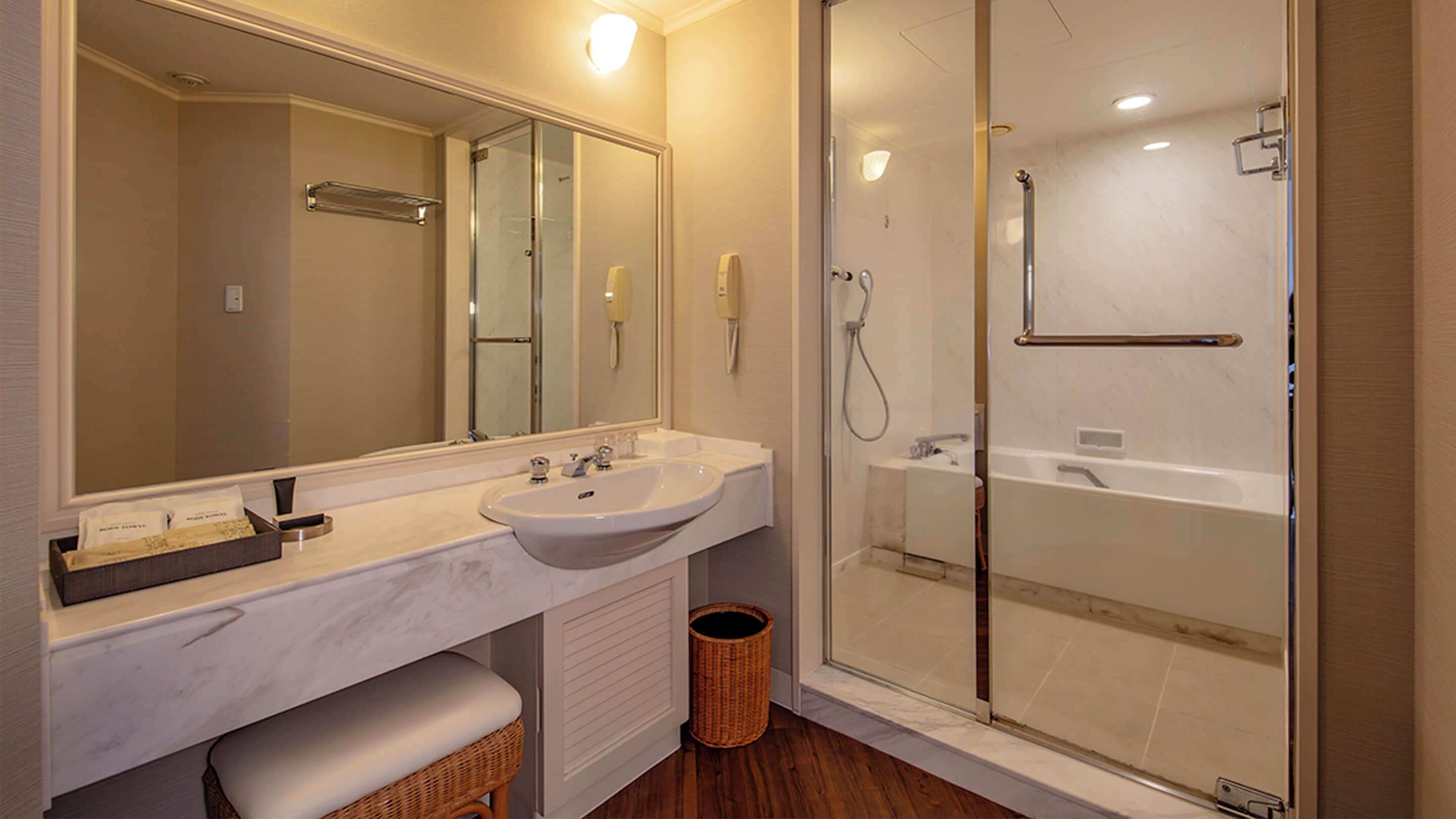 A bathroom with a large mirror, a sink, a shower, and a toilet.