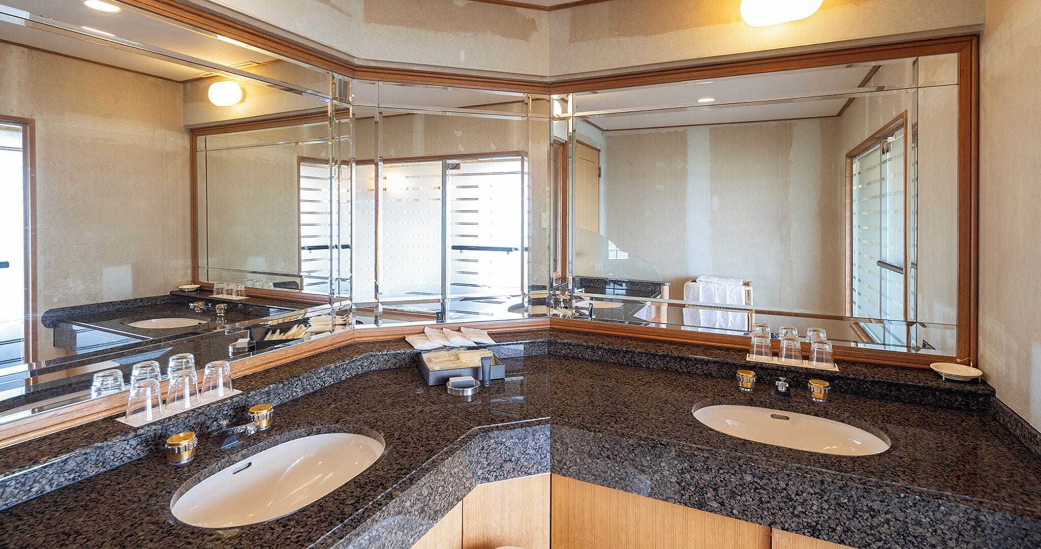 A hotel bathroom with two sinks, a large mirror, and a vanity area.