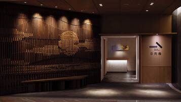 A modern interior with a wooden wall, a reception desk, and a sign indicating a Japanese cuisine restaurant.