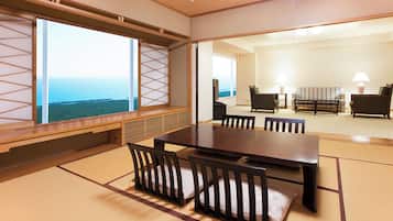 Een traditionele Japanse kamer met tatami vloeren, een lage tafel met stoelen en uitzicht op de zee door een shoji scherm.