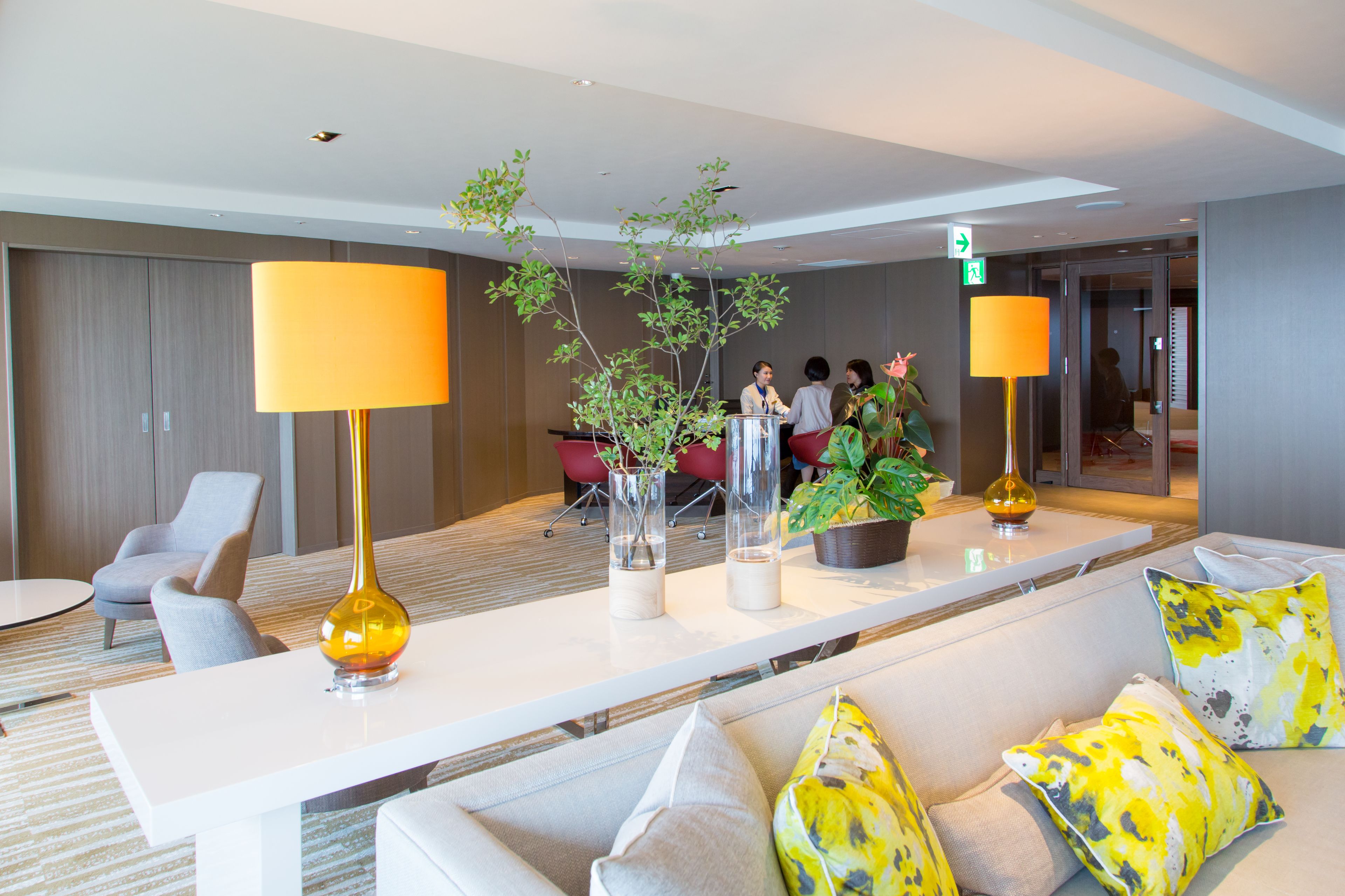 Un moderno vestíbulo de hotel con una recepción, zona de estar y plantas en macetas.