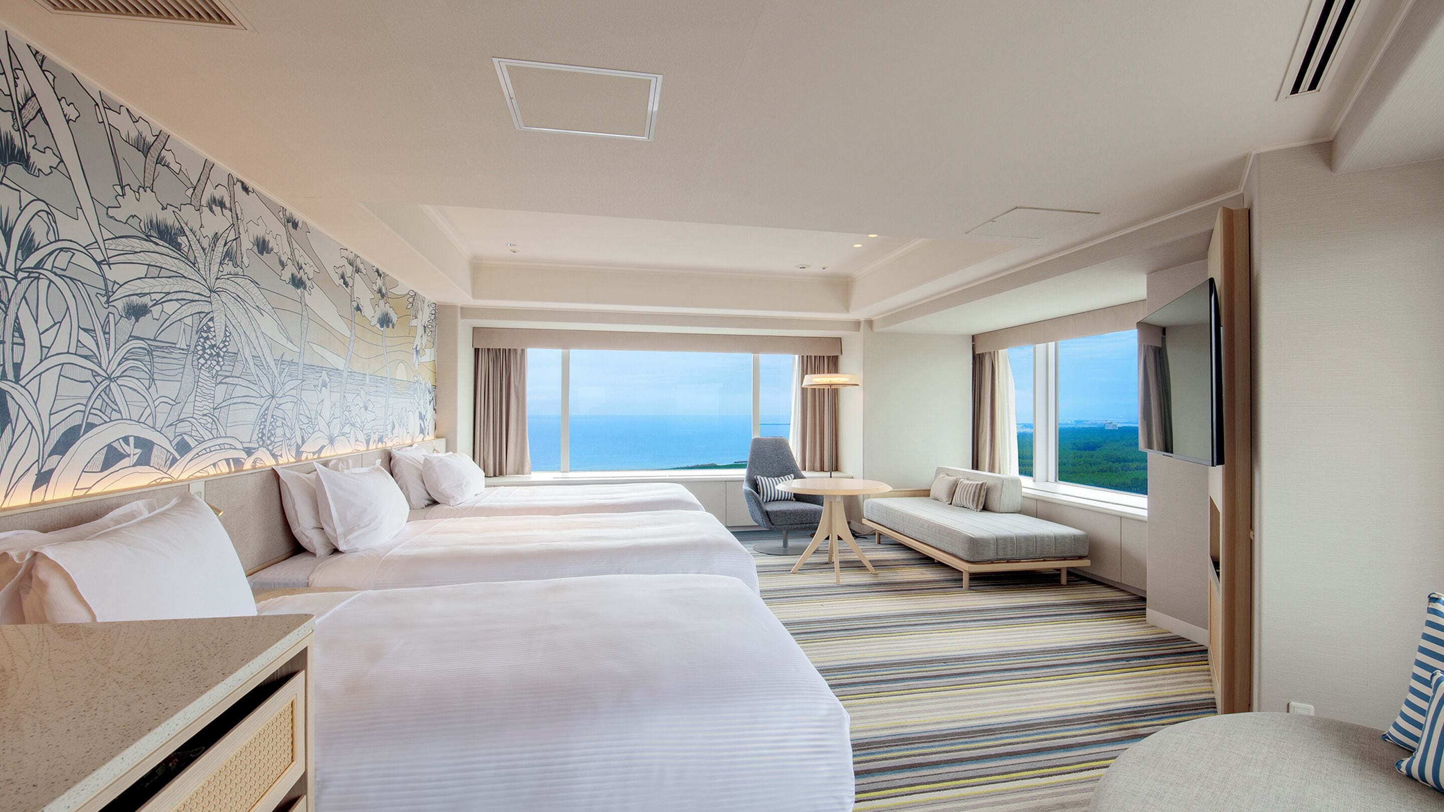 A hotel room with two beds, a sofa, a small table, and a TV.