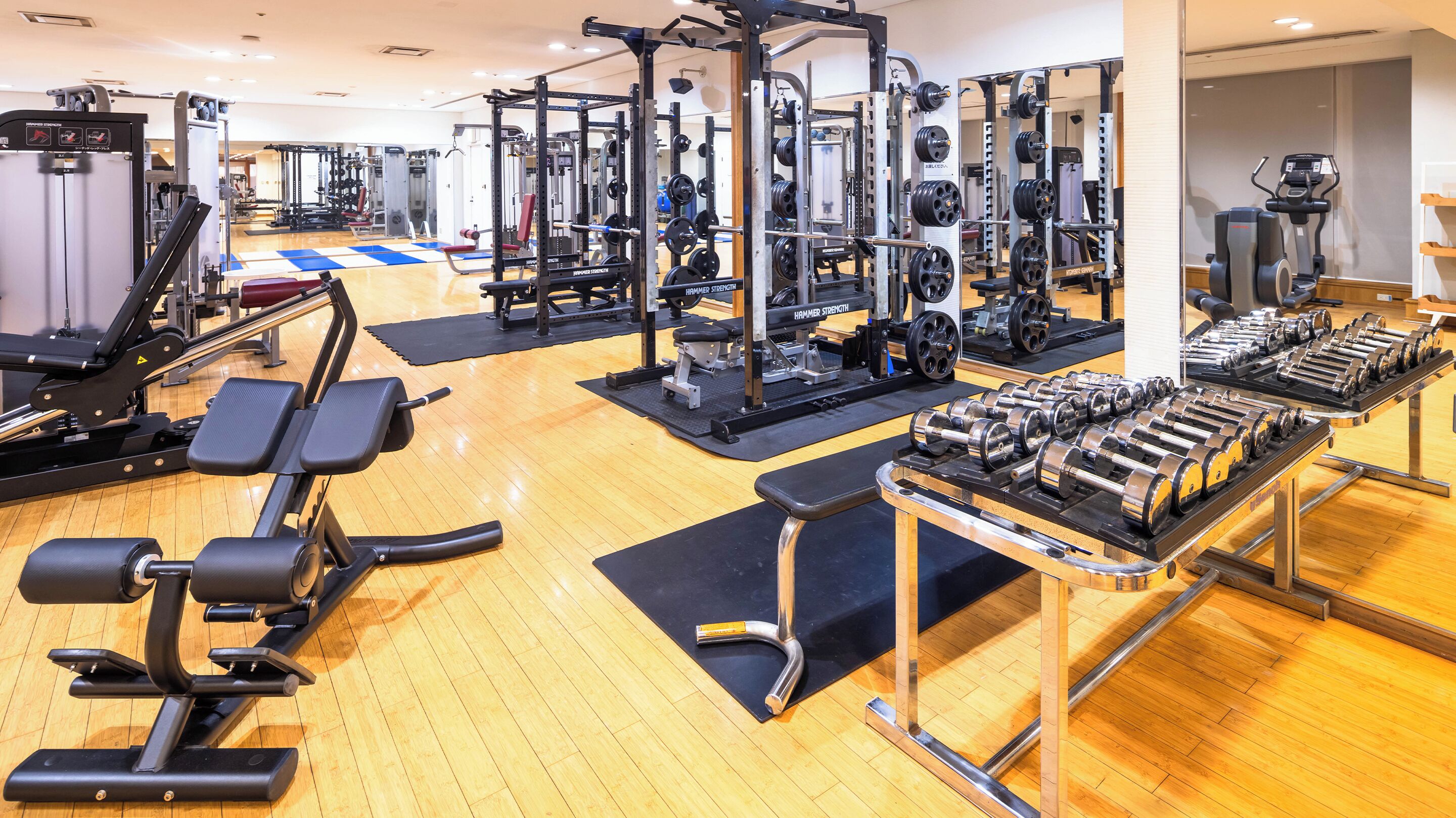 Una palestra con diverse attrezzature per l'allenamento, tra cui macchinari per pesi e manubri.