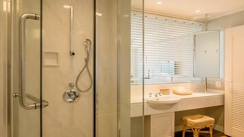 A modern bathroom with a glass-enclosed shower, a vanity with a sink, and a wooden stool.