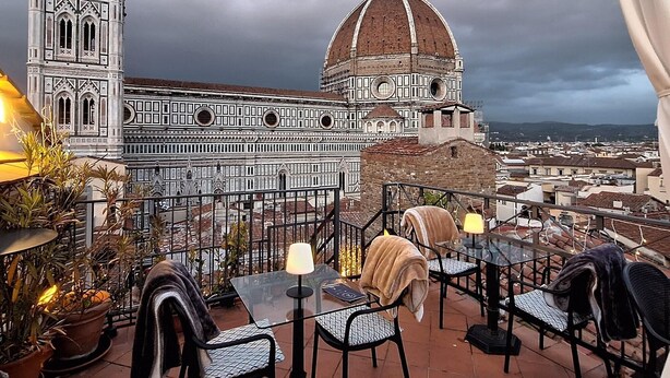 A terrace with outdoor seating and a view of a historic building with a bell tower and dome. - Hotel De Lanzi (Florence)